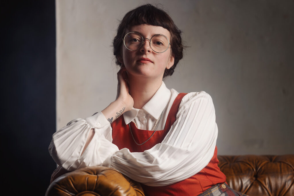 Jonge vrouw met klassieke kleding poseert met rode vouwfiets in binnenruimte